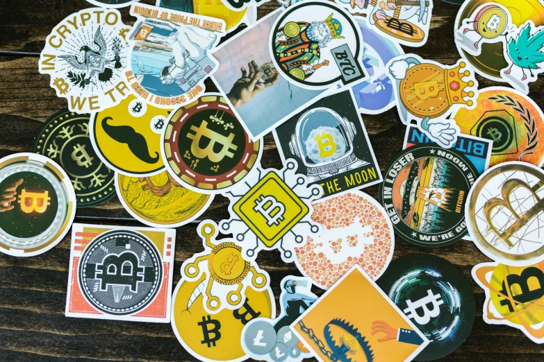 a pile of stickers sitting on top of a wooden table, giant crypto vault, 9 9 designs, bitcoin, collage