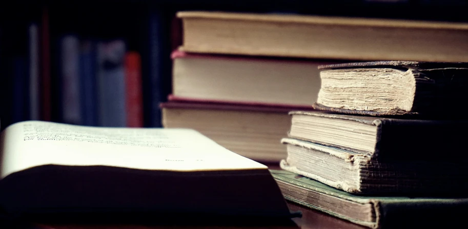 a stack of books sitting on top of a wooden table, archive material, dimly lit, instagram post, scientific study