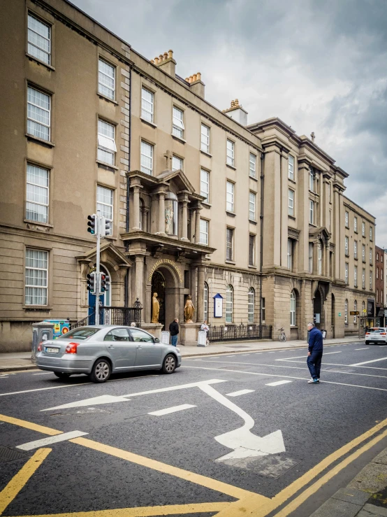 a car driving down a street next to tall buildings, a photo, by Anna Findlay, pexels contest winner, renaissance, book of kells, neoclassical police station, front elevation, square