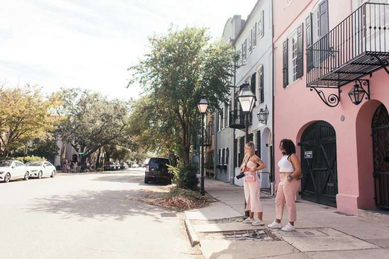 a couple of women standing next to each other on a sidewalk, by Elizabeth Charleston, pexels contest winner, pink color palette, savannah, panoramic view of girl, conde nast traveler photo