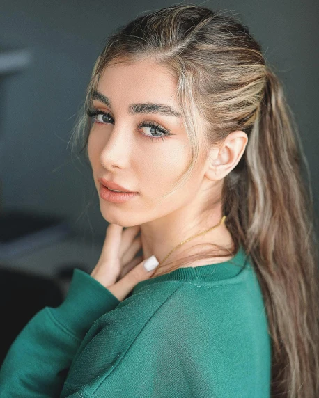 a woman with long hair wearing a green sweater, inspired by Julia Pishtar, trending on pexels, hurufiyya, tanned ameera al taweel, her hair is in a pony tail, ash blond greyish hair, charli bowater