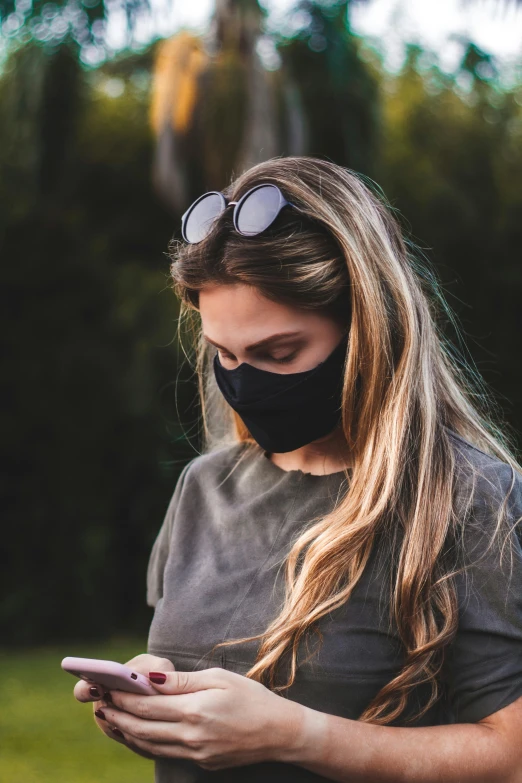 a woman wearing a face mask looking at her phone, casual black clothing, manuka, profile image, black main color