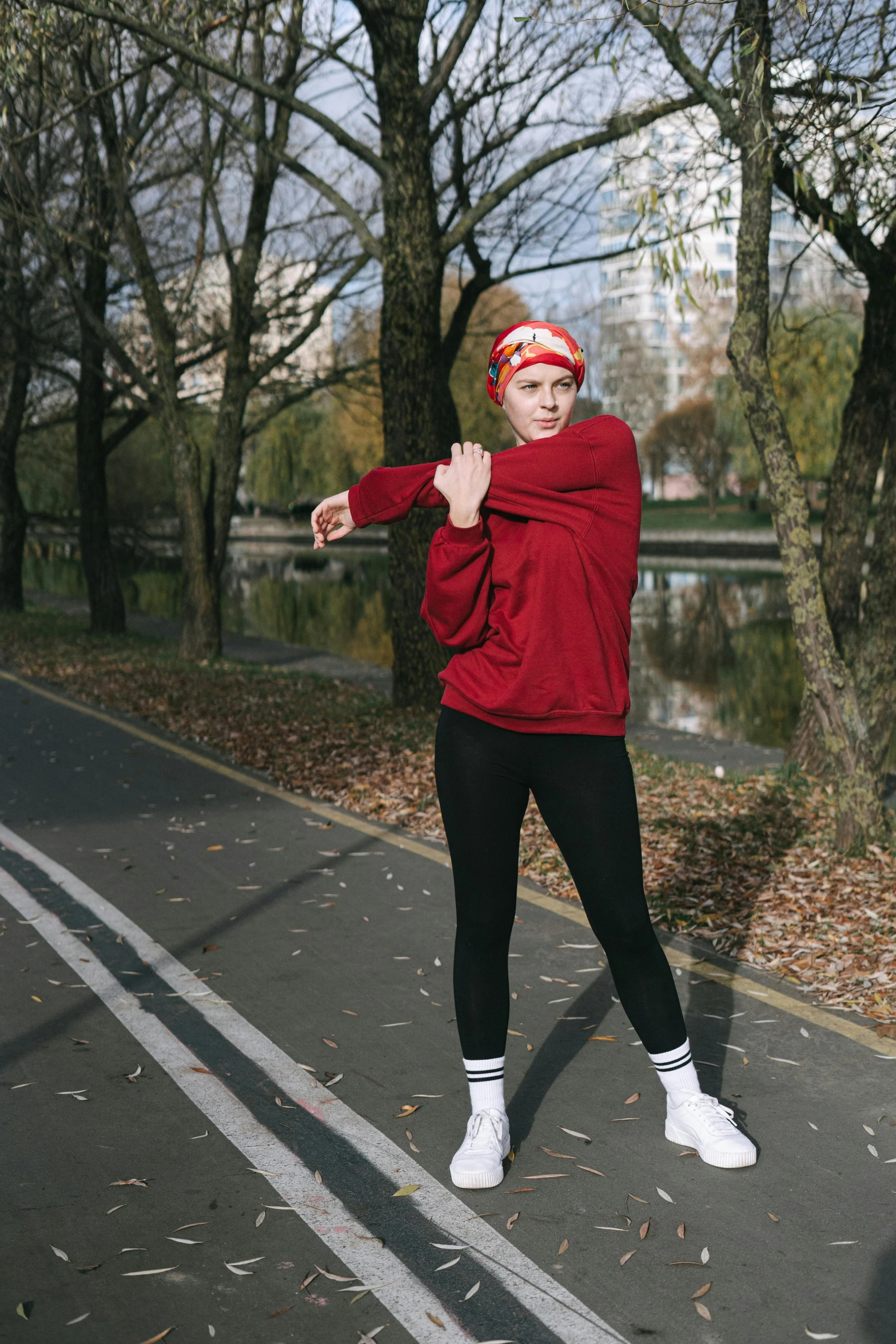 a woman standing on the side of a road holding a tennis racquet, by Attila Meszlenyi, happening, wearing a scarlet hoodie, rollerskaters, dynamic active running pose, wearing a backwards baseball cap