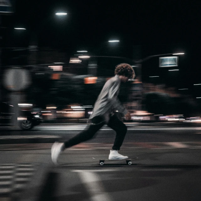 a man riding a skateboard down a street at night, unsplash contest winner, high speed, instagram picture, smooth background, desaturated