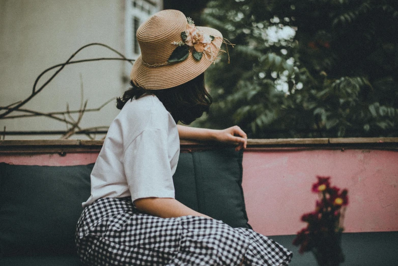 a woman sitting on a bench with a hat on, trending on pexels, layered skirts, girl with a flower head, sitting on the sofa, tumblr aesthetic