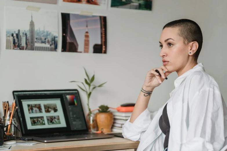 a woman sitting at a desk in front of a laptop computer, a photo, pexels contest winner, profile posing, portrait image, androgynous person, topknot