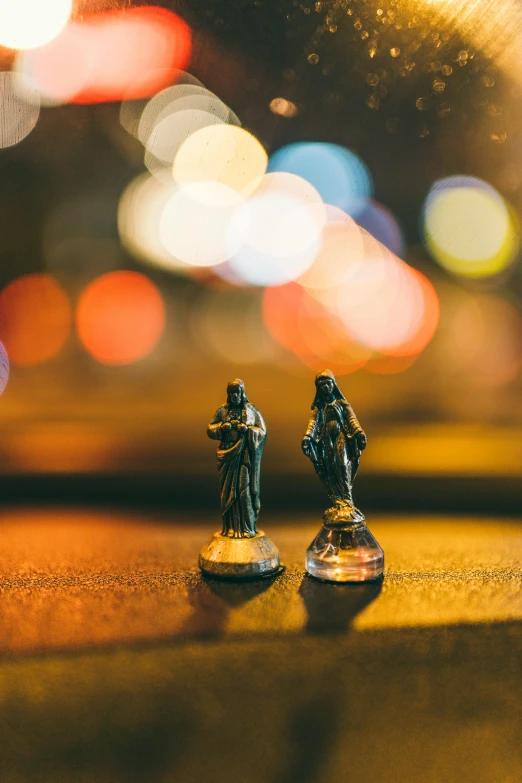 a couple of figurines sitting on top of a table, a statue, by Adam Marczyński, unsplash contest winner, holy lights, pair of keycards on table, glass and lights, high angle close up shot