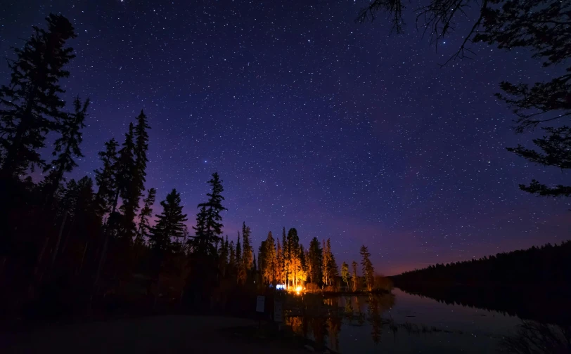 a campfire in the middle of a lake at night, by Jessie Algie, pexels contest winner, boreal forest, trees and stars background, cabin lights, gazing off into the horizon