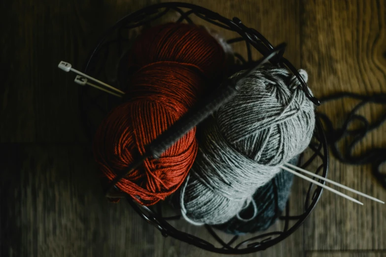 two balls of yarn in a basket with knitting needles, by Emma Andijewska, pexels contest winner, crimson and grey color scheme, dark hues, fishing, thumbnail