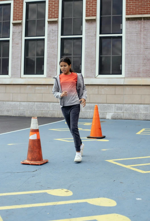 a woman running across a parking lot in front of a building, dribble, cone shaped, grey orange, school, promo image