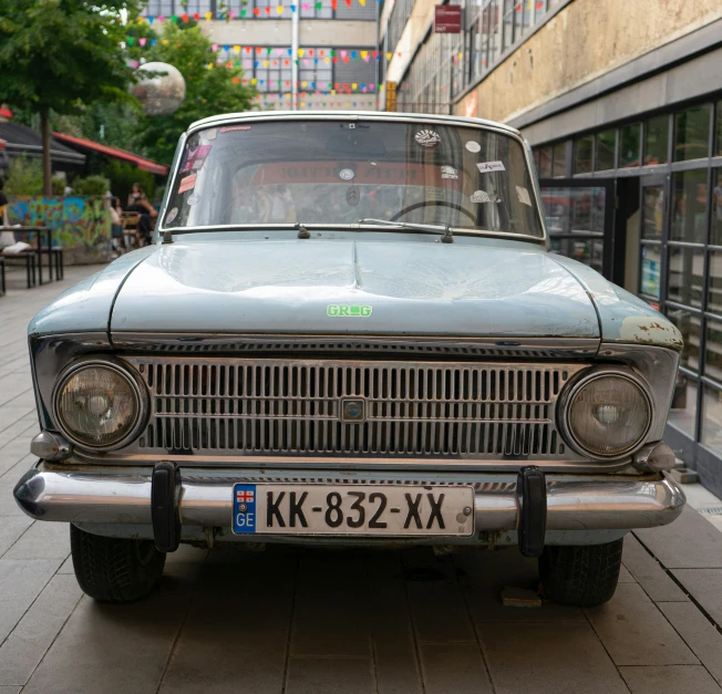 an old car is parked on the side of the street, by Sven Erixson, lada, front facing shot, square, high quality photo