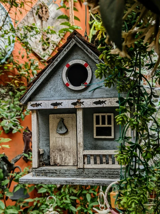 a birdhouse hanging from a tree in a garden, a colorized photo, pexels contest winner, tiny ornate windows, mini model, grey, neighborhood