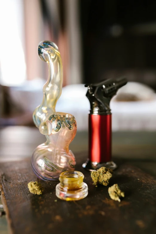 a glass pipe sitting on top of a wooden table, various items, with red haze, hemp, large tall