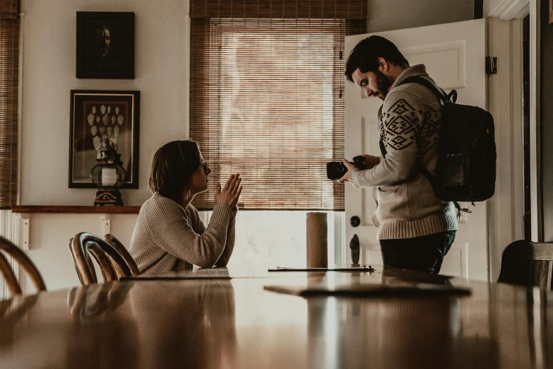 a man and a woman sitting at a table, a picture, by Marshall Arisman, pexels contest winner, hurufiyya, holding a camera, praying, man proposing his girlfriend, sitting across the room