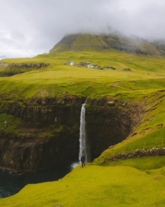 a couple of sheep standing on top of a lush green hillside, pexels contest winner, solitude under a waterfall, balaskas, cliffside town, a photo of the ocean