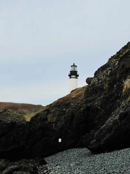 a lighthouse sitting on top of a rocky hill, posing for a picture