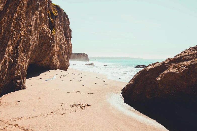 a sandy beach next to a cliff on a sunny day, pexels contest winner, renaissance, los angelos, retro vibe, sparkling cove, youtube thumbnail