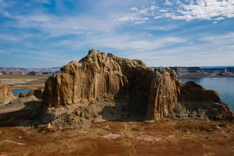 a large rock formation in the middle of a lake, by Lee Loughridge, unsplash contest winner, land art, mesa plateau, chrome cathedrals, wide high angle view, skies behind
