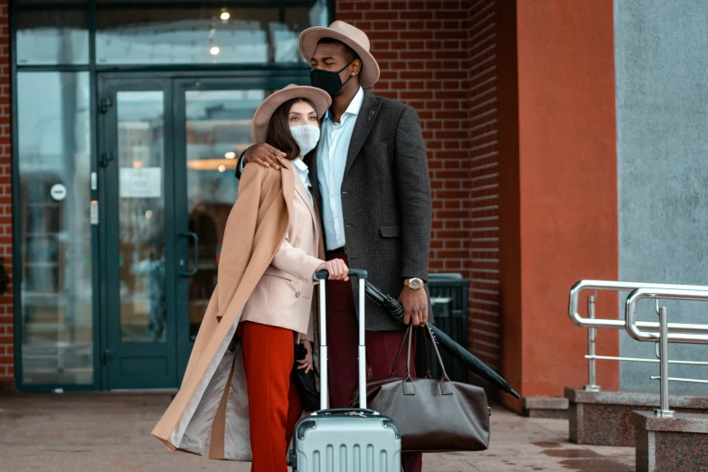 a man and woman standing next to each other with luggage, pexels contest winner, people are wearing masks, light brown coat, diverse outfits, romantic lead