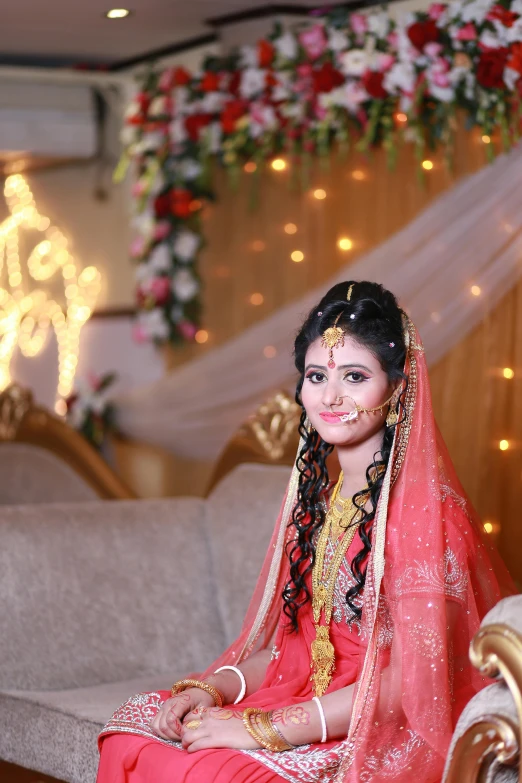 a woman sitting on a couch in a room, by Riza Abbasi, wedding, facing camera, fair complexion, high quality upload