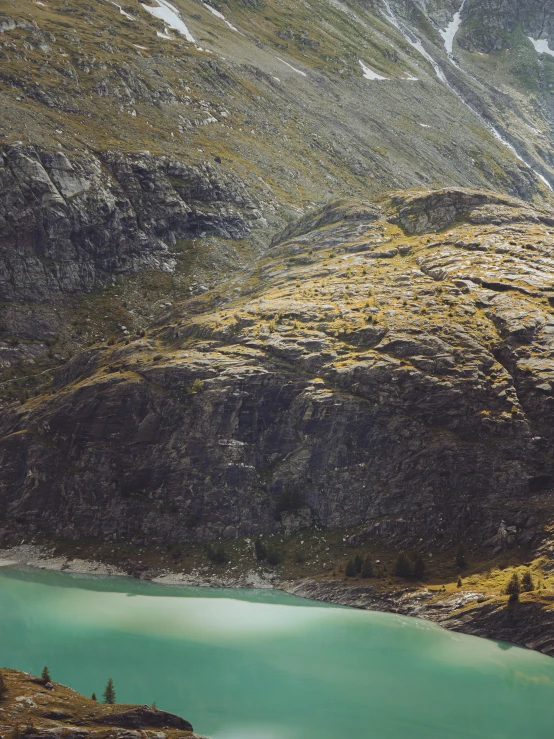 a man standing on top of a mountain next to a lake, taken from a plane, teal color graded, malika favre, slightly tanned