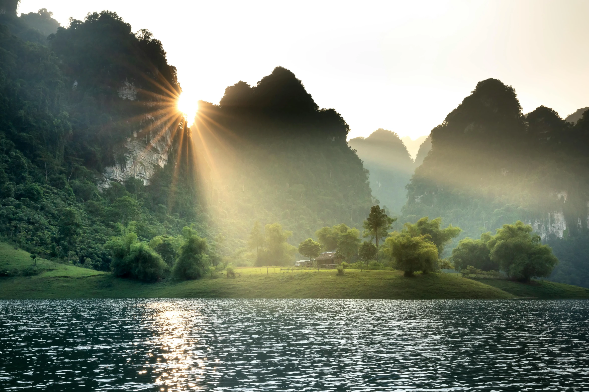 a large body of water with mountains in the background, pexels contest winner, romanticism, asian sun, karst landscape, lush valley, beams of light