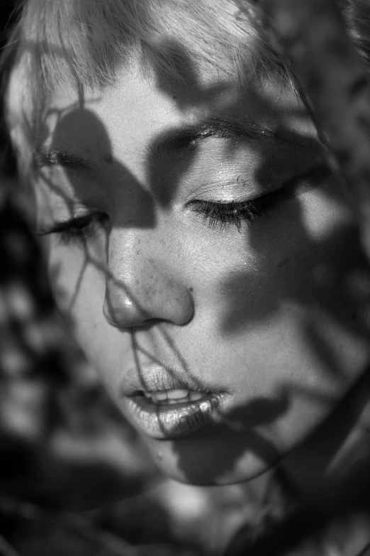 a black and white photo of a woman with her eyes closed, inspired by Max Dupain, unsplash, photorealism, reflections. shady, scars on face, shot at golden hour, dappled