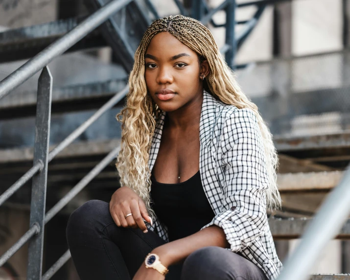 a woman sitting on the steps of a building, trending on pexels, visual art, box braids, sitting on a metal throne, blonde women, black young woman