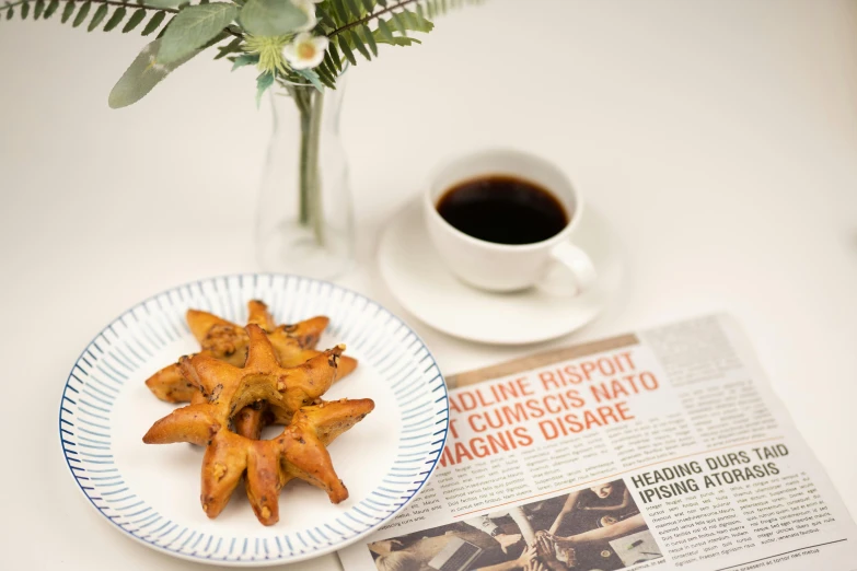 a plate of food on a table next to a cup of coffee, inspired by Géza Dósa, private press, pastries, newspaper photo, stars, calatrava