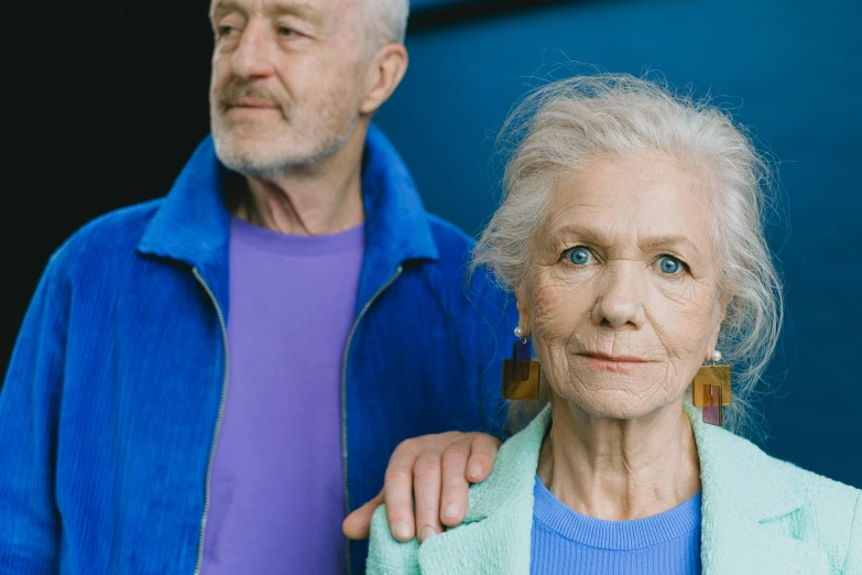 a man and a woman standing next to each other, a portrait, pexels contest winner, dementia, tired appearance, striking colour, looking her shoulder