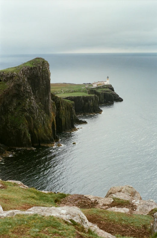 a couple of sheep standing on top of a lush green hillside, inspired by Thomas Struth, pexels contest winner, lighthouse, hazy water, skye meaker, view from above on seascape