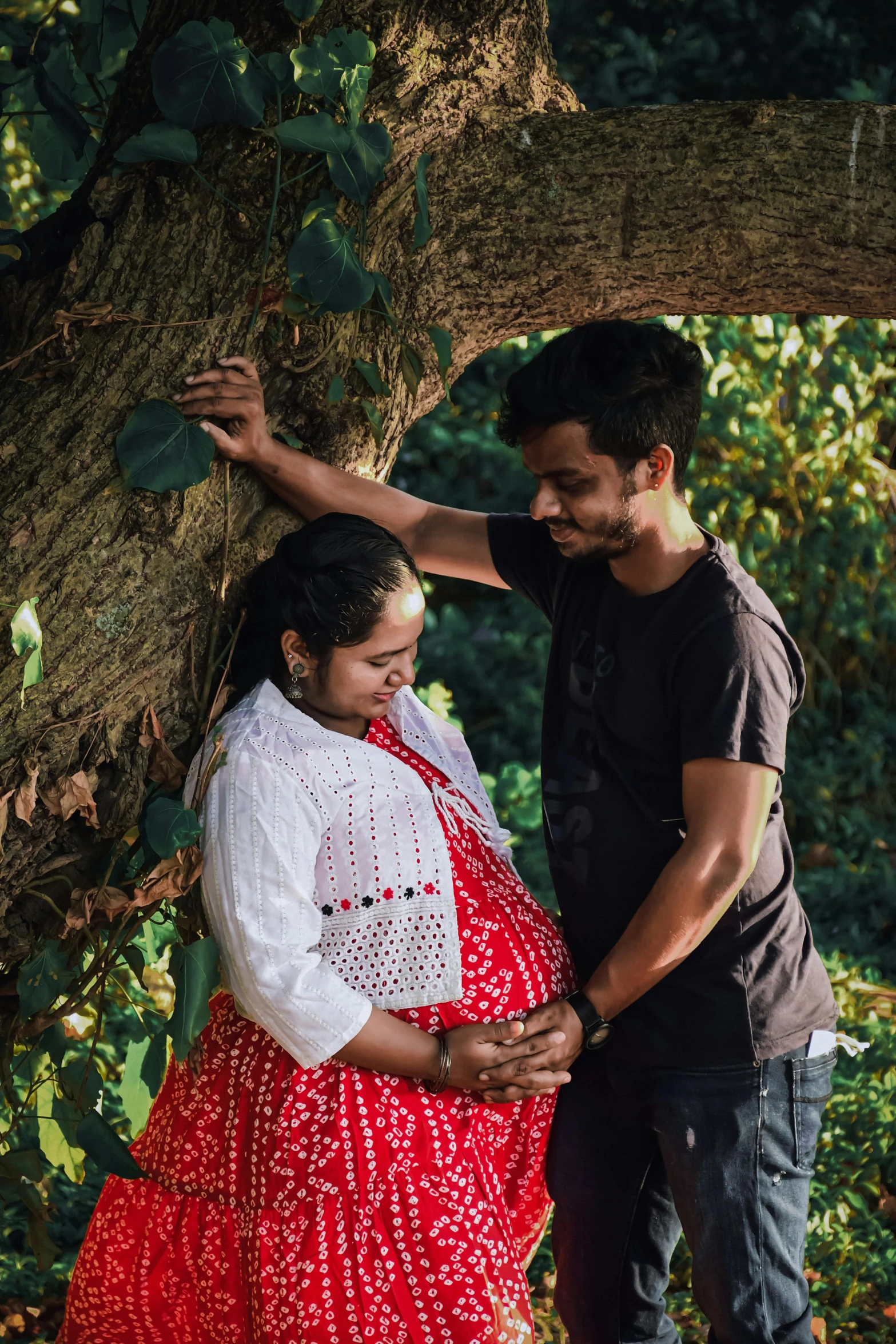 a pregnant woman standing next to a man under a tree, pexels contest winner, happening, provocative indian, boy and girl, supportive, profile image