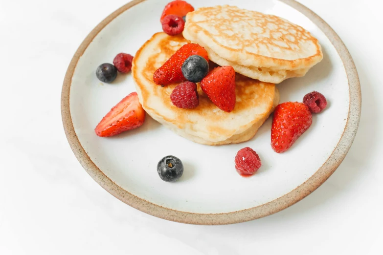 two pancakes with strawberries and blueberries on a plate, unsplash, 🦩🪐🐞👩🏻🦳, background image, crispy buns, bowl filled with food