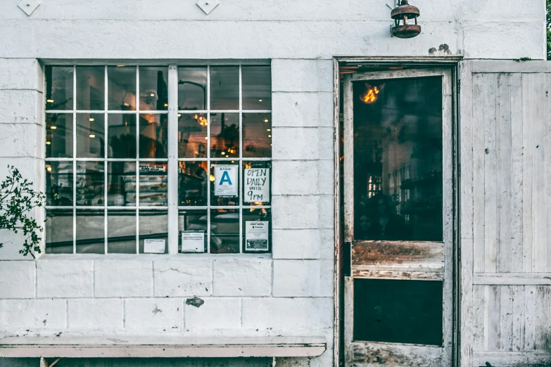 a wooden bench sitting in front of a white building, a photo, unsplash, private press, cute bakery shop, doorway, ignant, as well as scratches