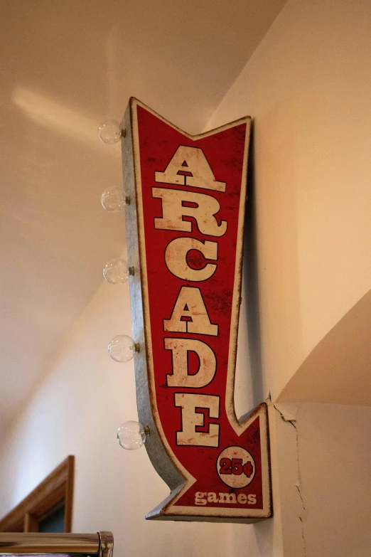 a red and white sign hanging from the side of a wall, featured on reddit, art nouveau, arcade cabinet, arcadia, 1900's, indoor light