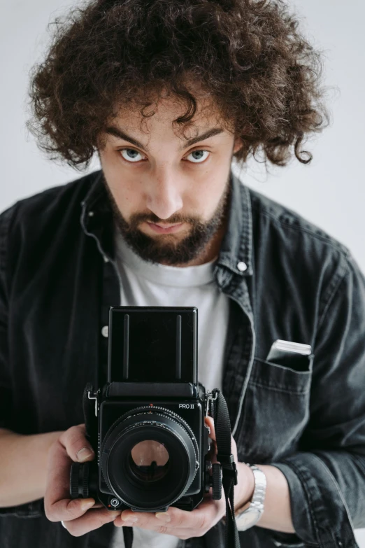 a man with curly hair holding a camera, pexels contest winner, photorealism, looking straight, gif, studio medium format photograph, staring hungrily