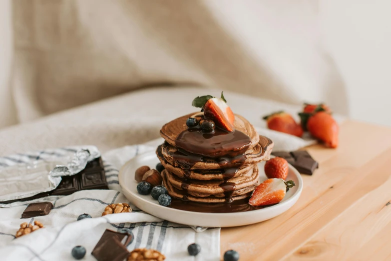 a stack of pancakes sitting on top of a wooden table, by Julia Pishtar, pexels contest winner, fully chocolate, botanicals, on a white table, 🎀 🧟 🍓 🧚