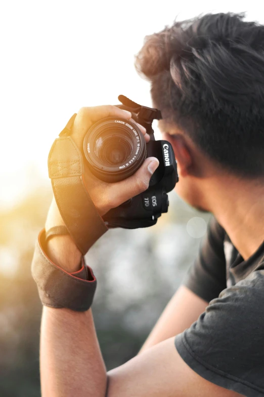 a man taking a picture with a camera, lens glare, facing away from the camera, shot with premium dslr camera, wave a hand at the camera