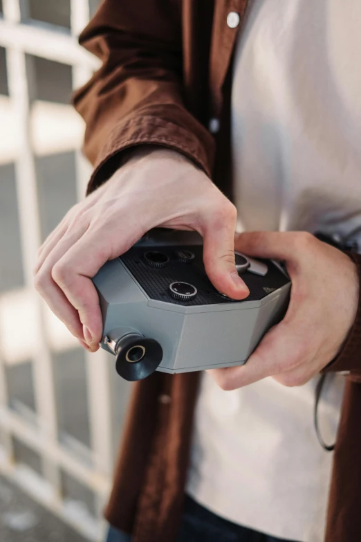 a person holding a video game controller in their hand, hasselblad camera, looking down on the camera, panoramic anamorphic, cinestill 400t