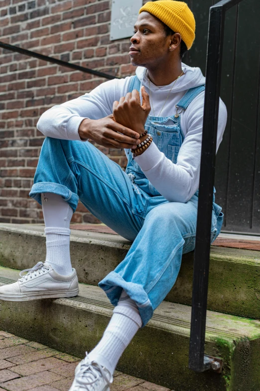 a man sitting on the steps of a building, by Jan Tengnagel, happening, wearing blue jean overalls, riyahd cassiem, cool white, official store photo