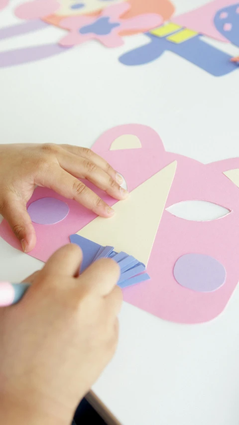 a person cutting out a piece of paper on a table, pink face, wearing wooden mask, -step 50, kids