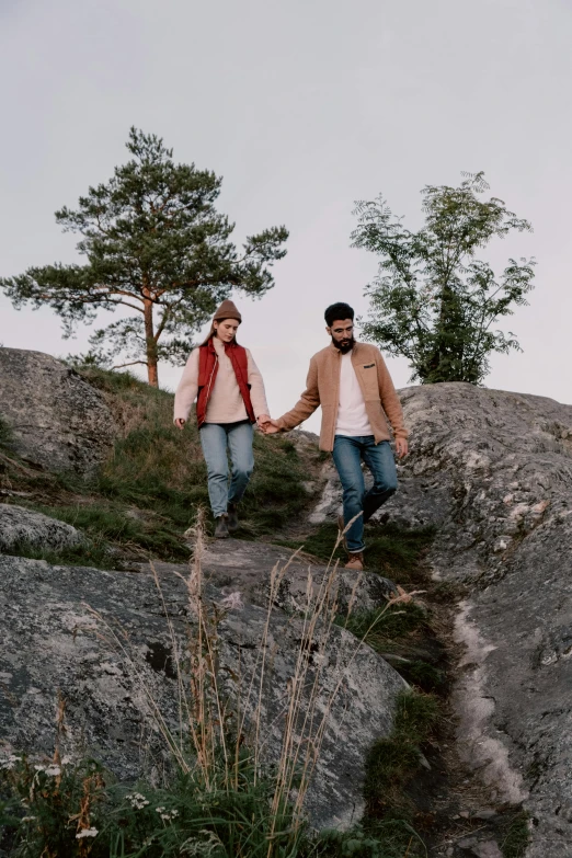 a man and a woman holding hands on top of a mountain, by Jaakko Mattila, trending on pexels, romanticism, standing on rocky ground, walking through the trees, wearing casual clothing, attractive photo