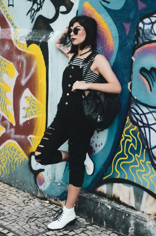 a woman leaning against a graffiti covered wall, a picture, wearing overalls, mall goth, são paulo, grunge aesthetic!!! (