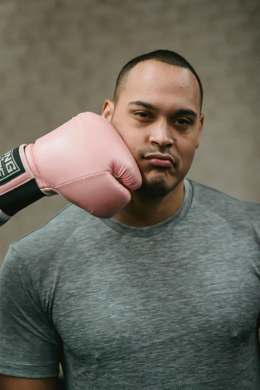 a man in a gray shirt and pink boxing gloves, an album cover, inspired by Gerald Kelly, pexels contest winner, samoan features, confident expression, manuka, square masculine jaw