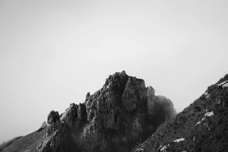 a black and white photo of a mountain, a black and white photo, unsplash, romanticism, craggy, foggy day, pareidolia, 4k vertical wallpaper