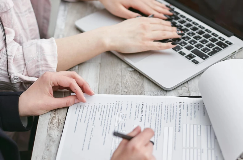 a couple of people sitting at a table with laptops, by Carey Morris, pexels, signing a bill, highly detailed rounded forms, bottom angle, selling insurance