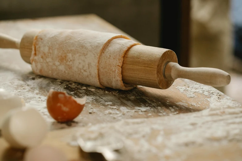 a rolling pin sitting on top of a wooden table, a still life, inspired by Sarah Lucas, trending on pexels, dough sculpture, in a workshop, award-winning crisp details”, pasta