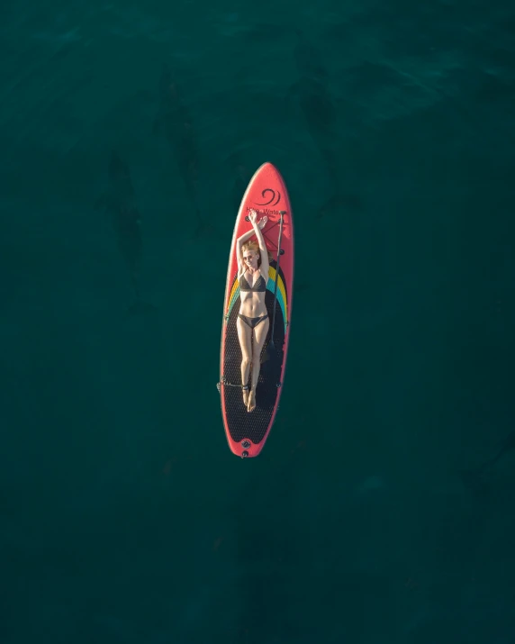 a woman riding a surfboard on top of a body of water, from above