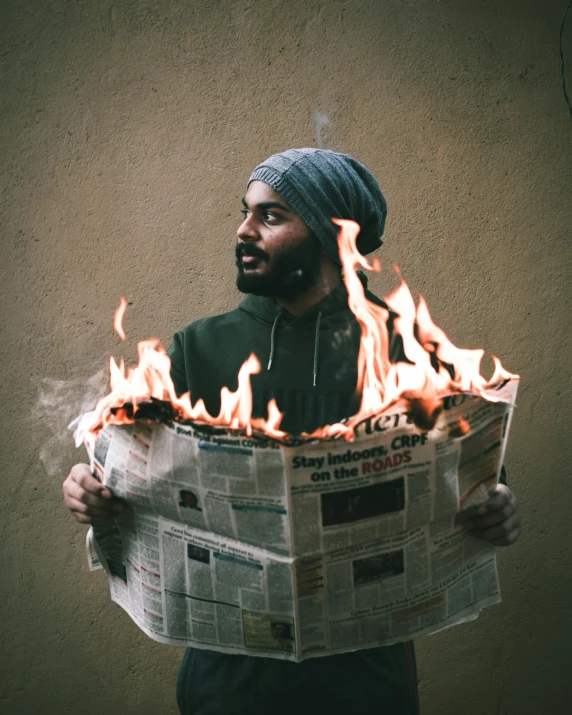 a man holding a burning newspaper in his hands, an album cover, pexels contest winner, turban, lgbt, tiny firespitter, no watermarks
