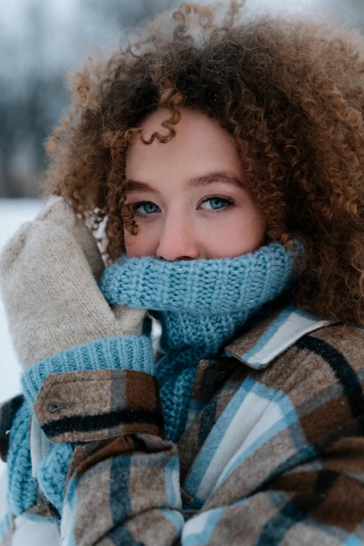 a close up of a person wearing gloves and a scarf, curly hair, freezing blue skin, girl with brown hair, portrait featured on unsplash